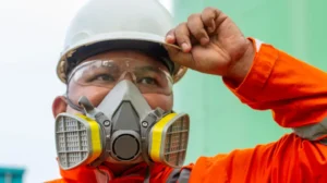 Man wearing PPE equipment including hard hat, a respirator and eye protection